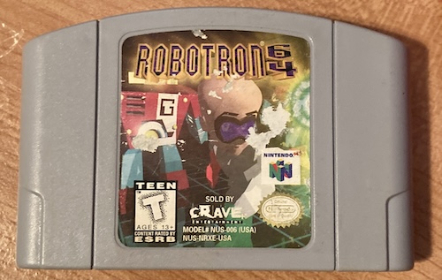A copy of Robotron 64, with a torn and tattered label, lying on my junky desktop.