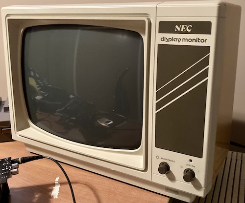 The JB-1260. It is an off-white cream colour with Tektura font reading "NEC display monitor." There are two dials on the front, one for power and one for brightness.