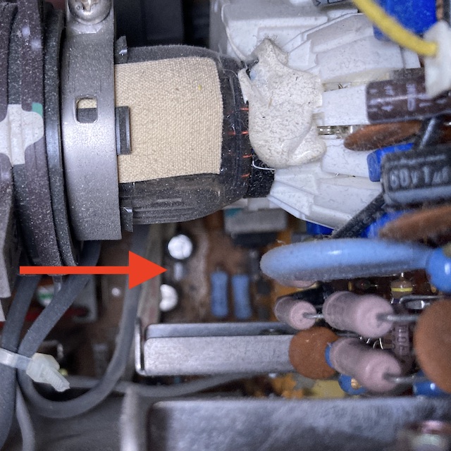 The CRT is glued onto the neckboard, but you can also see an odd reflection of the light coming from beneath two caps on the bottom bottom. A red arrow points to that odd reflection in case you can't see it. The neck board is in the foreground.