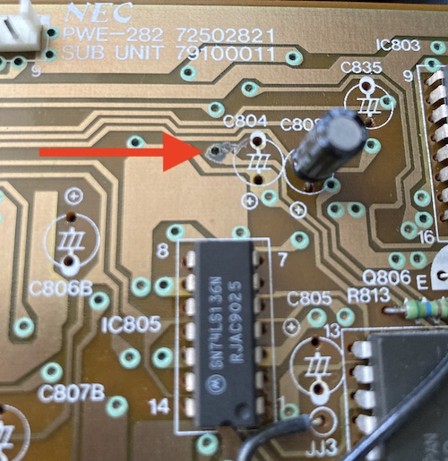 A red arrow is pointing to a suspicious blob of what turned out to be soldercrete on top of a protected via.