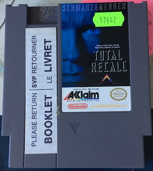 The Total Recall cartridge, before being opened. You can see a bilingual "PLEASE RETURN BOOKLET / SVP RETOURNER LE LIVRET" warning, as well as a "B" hot-branded into the plastic of the case.