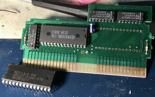 Total Recall's PRG ROM (right) has been neatly desoldered, instead of the CHR RAM (left) which I meant to desolder. The RAM is a Samsung KM6264 and the ROM is an NEC UPD23C1010AC-S19, with the build code NES-L4-0 PRG.