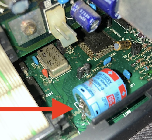 The battery, with an arrow pointing to the super-globby negative terminal.