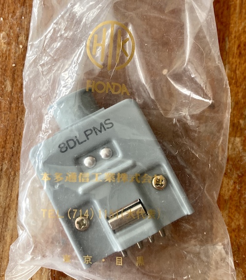 The connector in its shipping bag. The bag remarks "HTK," and then underneath it, Honda. In Japanese, it reads Honda Tsushin Kogyo Communications Division and has a telephone number (714) 1151. It says it comes from Kyoto.