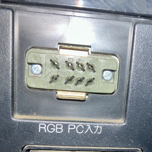 The RGB connector on the back of the PC-TV151. It's an eight-pin female connector, off-green plastic. It says "DND" on the body for some reason. Pins are 1 in the lower left going to 4 in the lower right, then 5 in the upper left going to 8 in the upper right. There is a gap between pins 1 and 2, and pins 5 and 6, to provide keying. There are recessed phillips head screws on each side, and a triangular relief in the plastic to indicate presumably which side is 1. Underneath the connector it says RGB PC 入力, or "input."