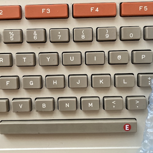 The space bar has a circular red sticker, with the letter "E" in white inside.