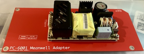 The Meanwell RPT-60B AC-DC power supply is bolted to the red mounting PCB. It looks like a complex PCB on top of a simple PCB.