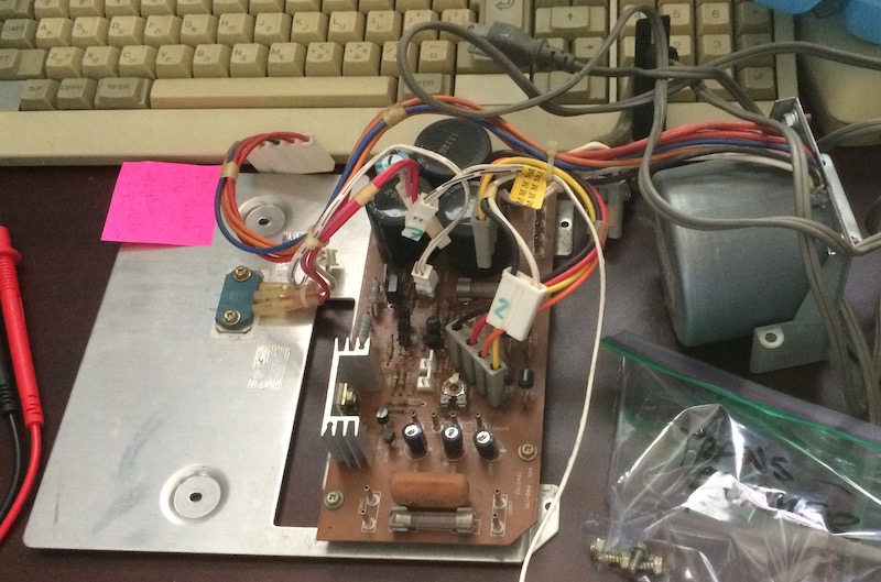 The power supply board and transformer sitting on the table. There's also the hard-wired electrical cord on it.