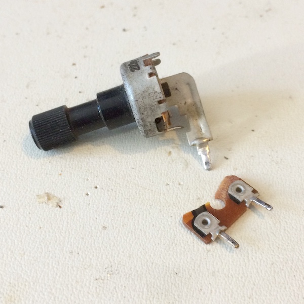 The potentiometer lying on my workbench in two halves. The bottom half is in the foreground.