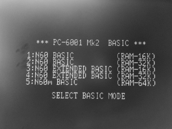PC-6001mkII running. The screen says PC-6001 Mk2 BASIC 1) N60 BASIC RAM-16K, 2) N60 BASIC RAM-32K, 3) N60 EXTENDED BASIC RAM-16K, 4) N60 EXTENDED BASIC RAM-32K, 5) N60m BASIC RAM-64K