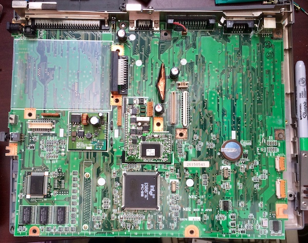 The top of the PC-9801NS/T motherboard. Near the bottom of the board is a letter code for which horizontal sector a component lives within.