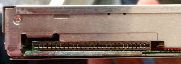 The back of the floppy drive. The port has blue-green corrosion stuck inside it and also soaked into the PCB substrate.