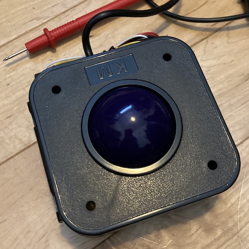 The arcade trackball, lying on the scarred wooden floor of my office.