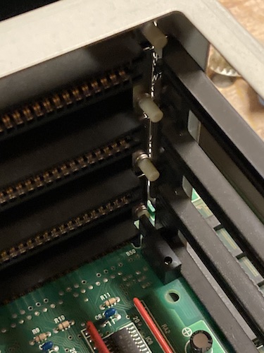 There's a little plastic finger on the back of the SCSI card which pushes on a little button on its corresponding slot.