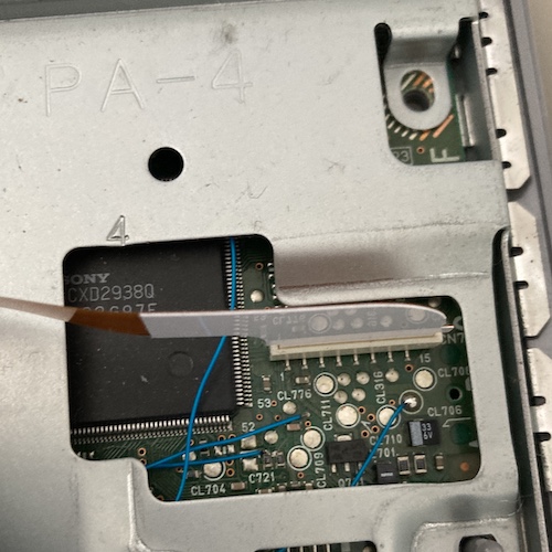 Blue wires are running all over the motherboard, as seen through this hole in the RF shielding.