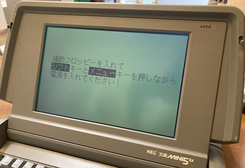 The mini5SX is displaying an error screen in enormous Japanese text. Its screen is backlit.