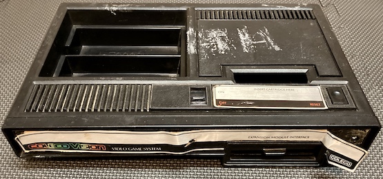 The ColecoVision, in normal lighting. You can see more clearly now that the stickers are loose and there's a lot of gunk in the entire console.
