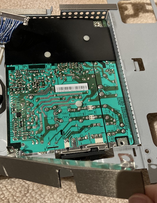The padded cover is pulled up so that the power supply's black plastic cover around the plug and switch can slide up through a hole in the case.