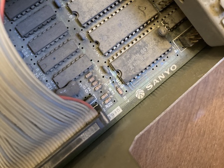 The thick layer of dust covering every chip has failed to obscure the Sanyo logo. There is, however, a hated tantalum capacitor right there near the keyboard controller.