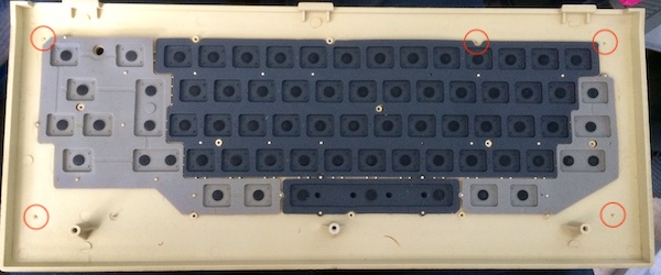 The underside of the keyboard plastic with rubber membranes inserted. The five broken posts are highlighted in red circles.