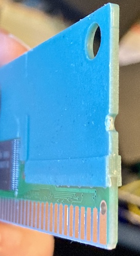 A chunk of blue-grey plastic is bonded onto the PCB, holding it rigidly.