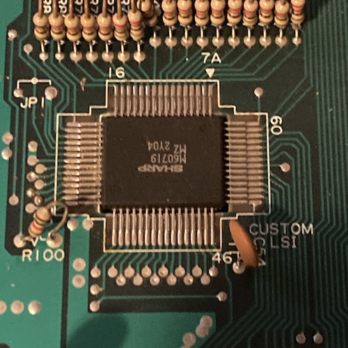 A QFP marked "Custom LSI" on the motherboard is pictured. Its label is Sharp M60719 MZ 2Y04, and it appears to have 60 pins, with 16 pins on each long side and 14 pins on each short side. A silkscreen mark is pointing to pin 1 with the legend "7A."
