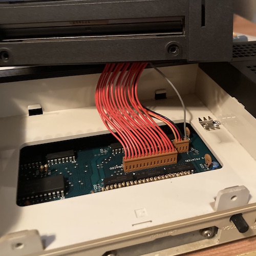 The plotter is pulled up, exposing the plastic tray it sits in, the nubs that keep it retained, and the cables that connect it to the motherboard.