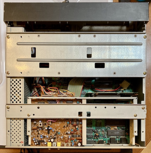 The inside of the case is exposed. Along the left side is a very long power supply, then there is a yellow "Telopper" board, and two large green boards that comprise the computer.