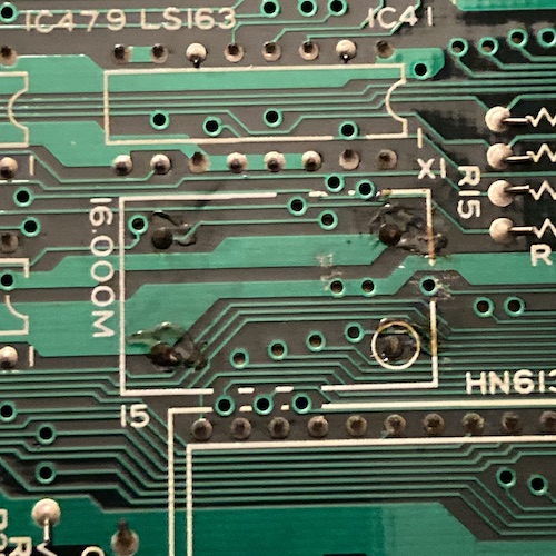 The 16MHz oscillator on the I/O board shows signs of rework. The solder joints are burned and not well-formed. A lot of old flux is spilled around.