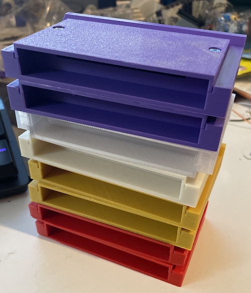 A stack of 3D-printed cartridge shells, in (from the top) purple, clear, white, yellow, and red.