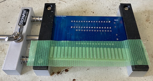 Green solder tape is placed over the edge connector during the assembly of the board.