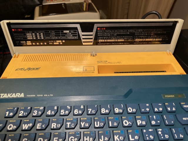 The yellow door has pulled up to expose the cartridge slot. It has lots of instructions about how to use the BASIC cartridge in it.