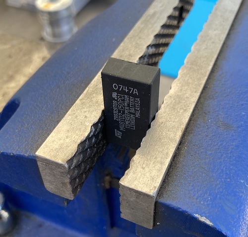 The M48T02 chip has been inserted into the jaws of a regular ol' blue garage vise, pin 12/13 facing up.