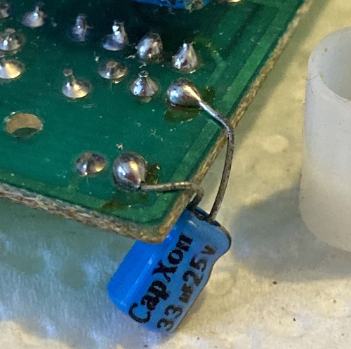 A blue CapXon branded 33µF/25V cap loosely dangled off the bottom of the top board.