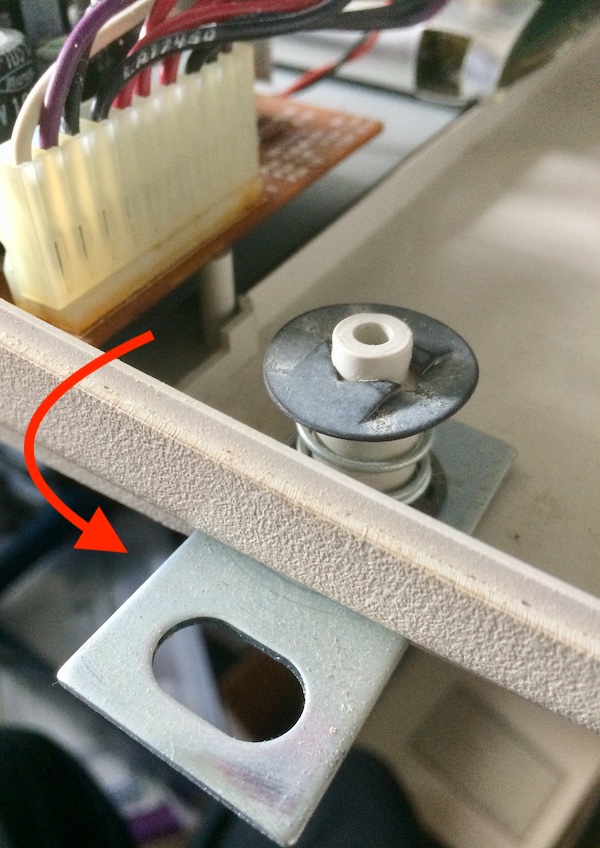 The metal prong is rotated out the side of the computer. An arrow shows its path of rotation.