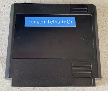 The cartridge in its finished form, with a blue thermal label on the lid reading "Tengen Tetris (FC)." My dirty ESD mat lays behind.