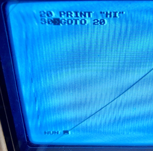 A small BASIC program is entered: 20 PRINT "HI" 30 GOTO 20 but at the bottom of the screen it says "NUN" instead of "RUN." All lines of the BASIC program are indented by one space to avoid corrupting the first character.