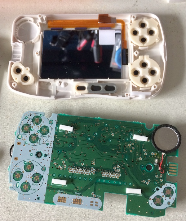 The WonderSwan front case removed from the motherboard. You can see a loose motherboard and a loose front case.