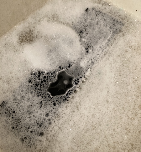 The black fascia beneath the bubbly waves of my utility sink.