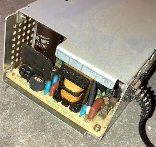 Looking inside the power supply. It looks fairly clean except for gunk around the main fuse and on top of the bridge rectifier. Large Nichicon caps are visible.