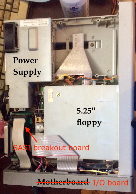 X68000 power supply side. The power supply, an empty hard drive bay, one of the 5.25" floppy drives, and a SCSI breakout board are exposed.