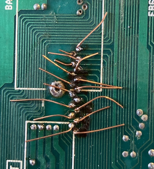 The backside of the trace repair has a bunch of loose wires sticking out, along with a sticky black blob.