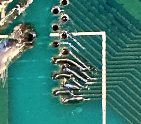Six traces are patched with solder-covered wires. There are some ugly solder globs on them, and the traces are still partially exposed in places.